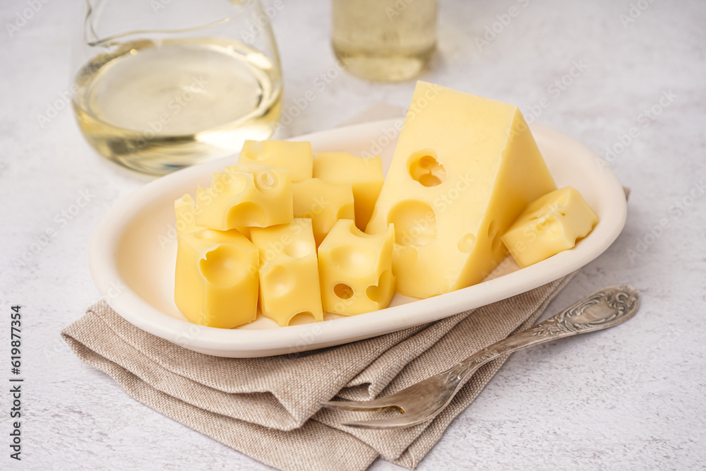 Plate with pieces of Swiss cheese on white table