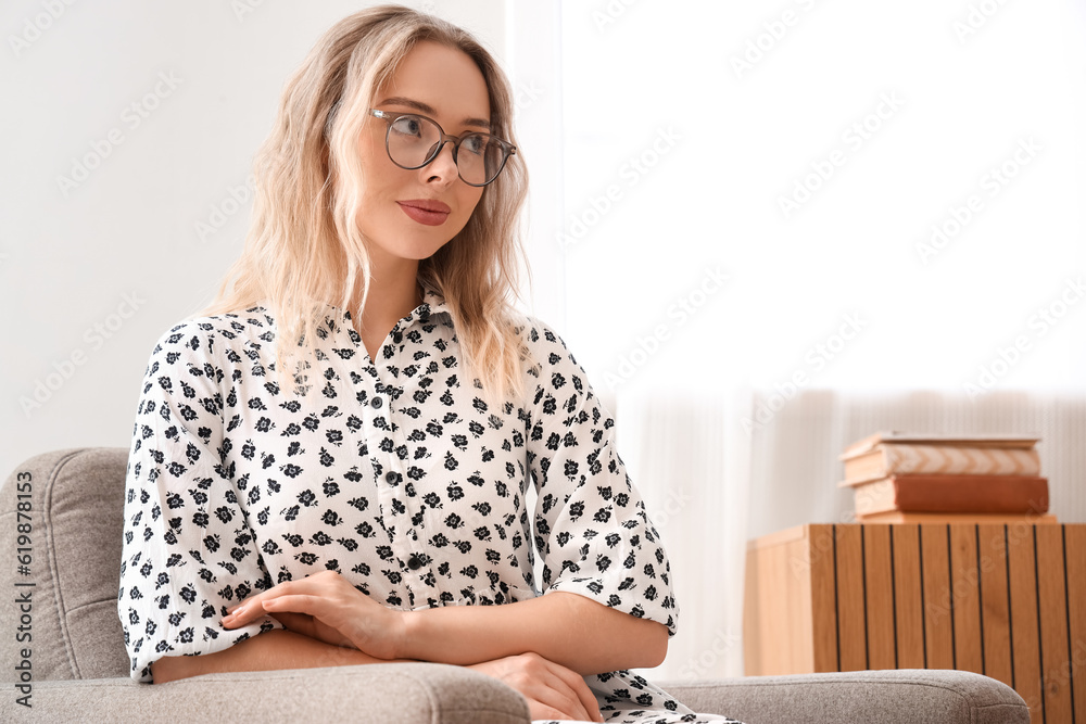 Young woman in stylish eyeglasses sitting at home