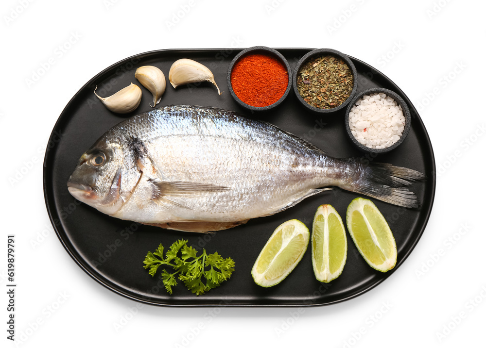 Tray of raw dorado fish with lime and spices on white background