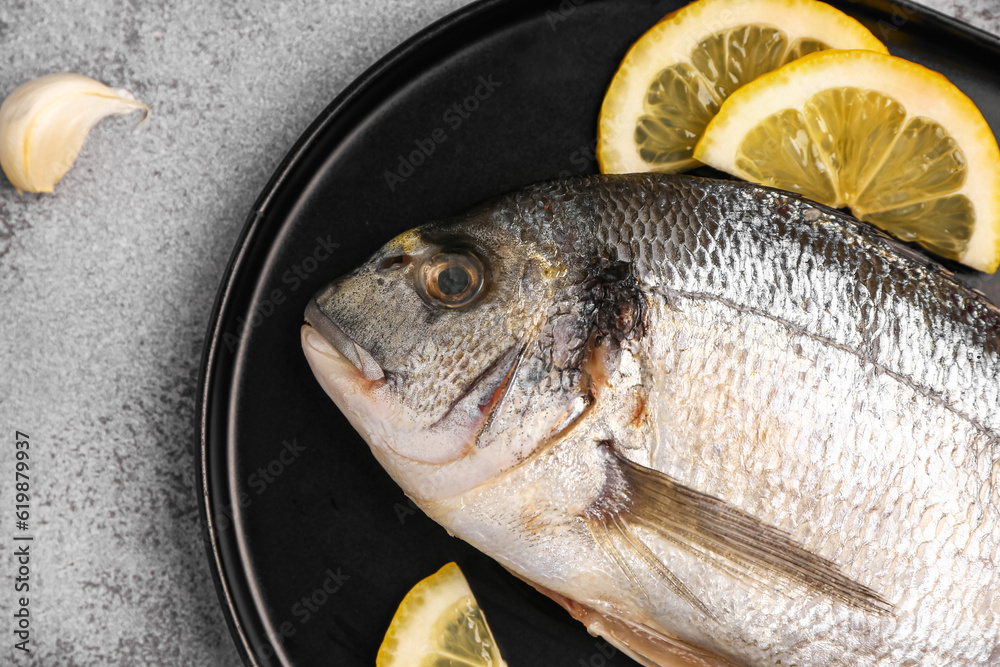 Tray of raw dorado fish with lemon on light background