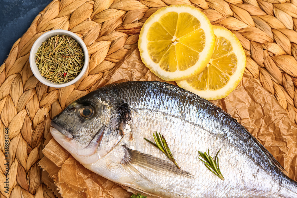 Raw dorado fish with lemon and herbs on table