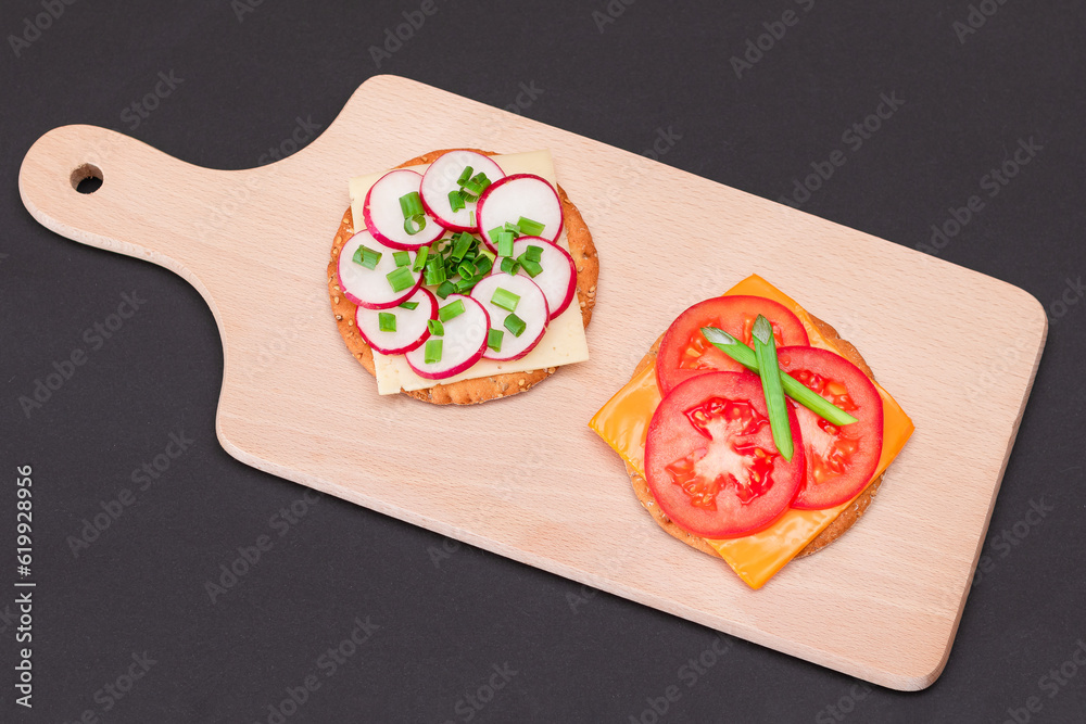 Different Cracker Sandwiches with Tomato, Cucumber, Radish and Cheese on Cutting Board. Easy Breakfa