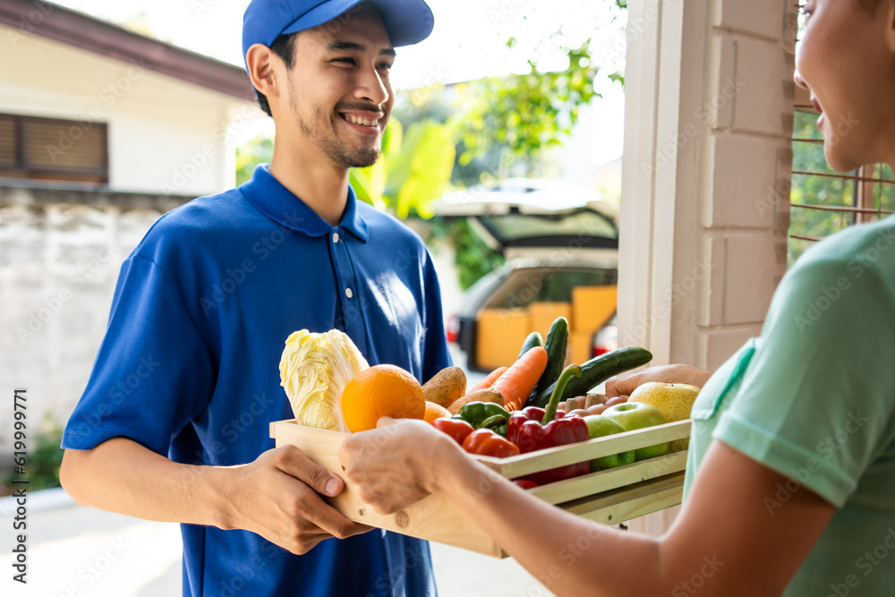 Asian young delivery man delivering package to female customer at home. 