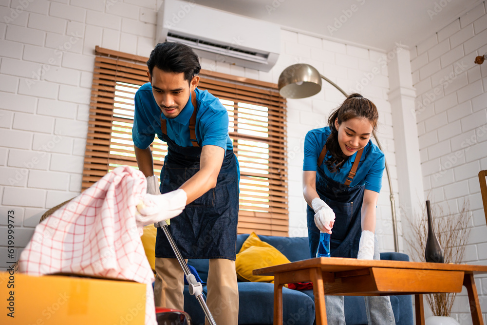 Asian young man and woman cleaning service worker work in living room. 