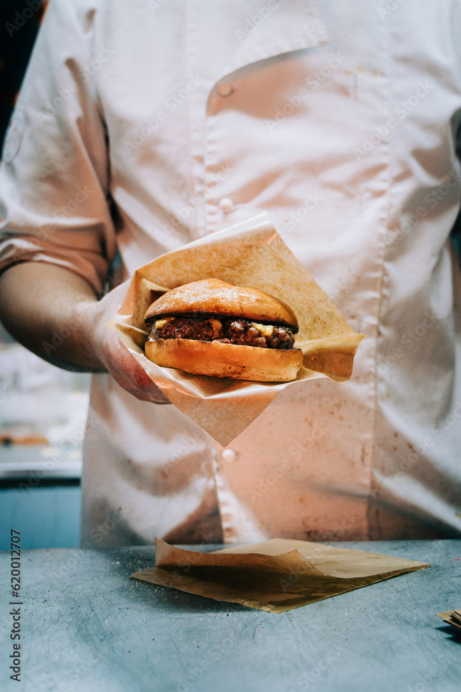 Chef holding hamburger with cheese in a food truck