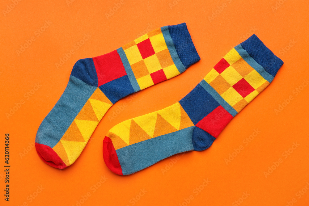 Pair of stylish socks on orange background