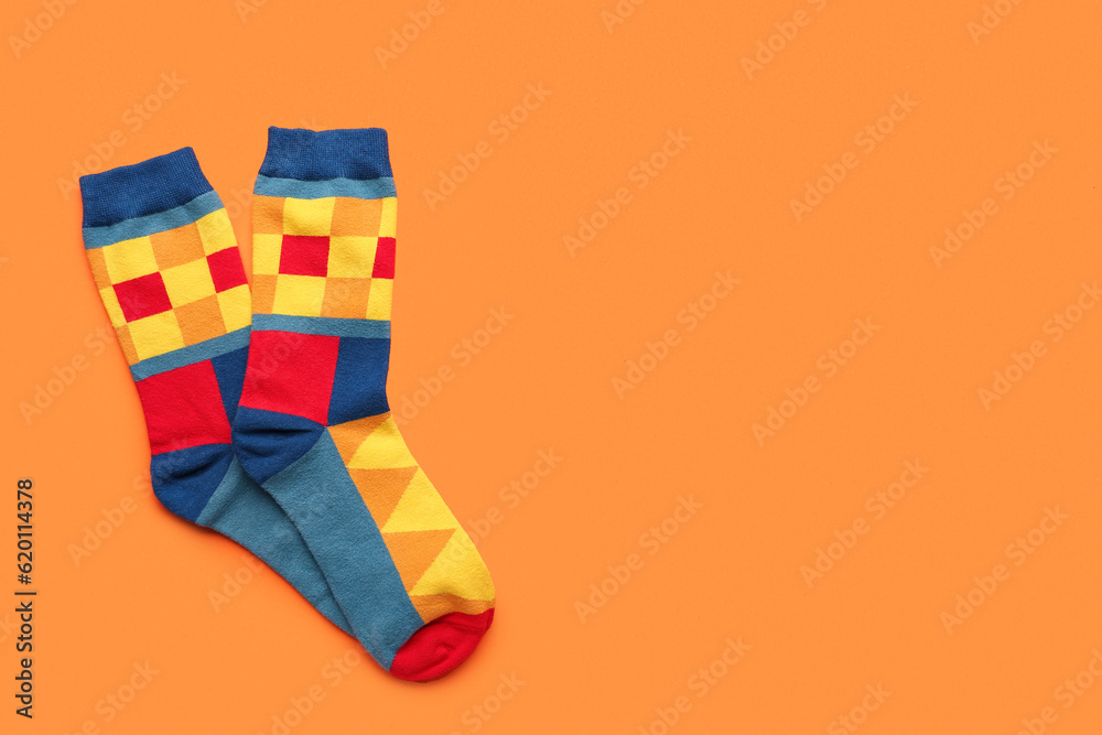 Pair of stylish socks on orange background