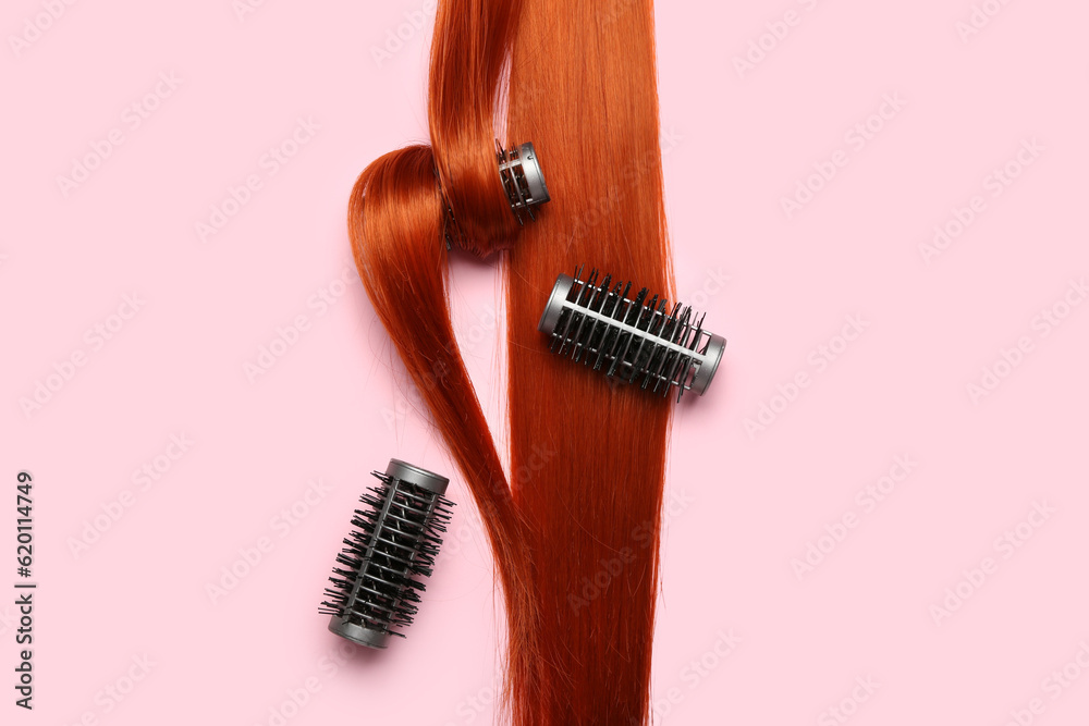 Ginger hair strand with curlers on pink background