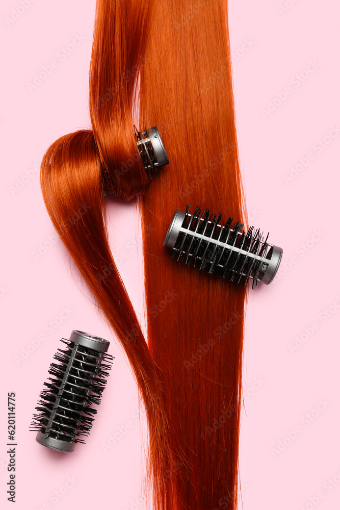 Ginger hair strand with curlers on pink background, closeup