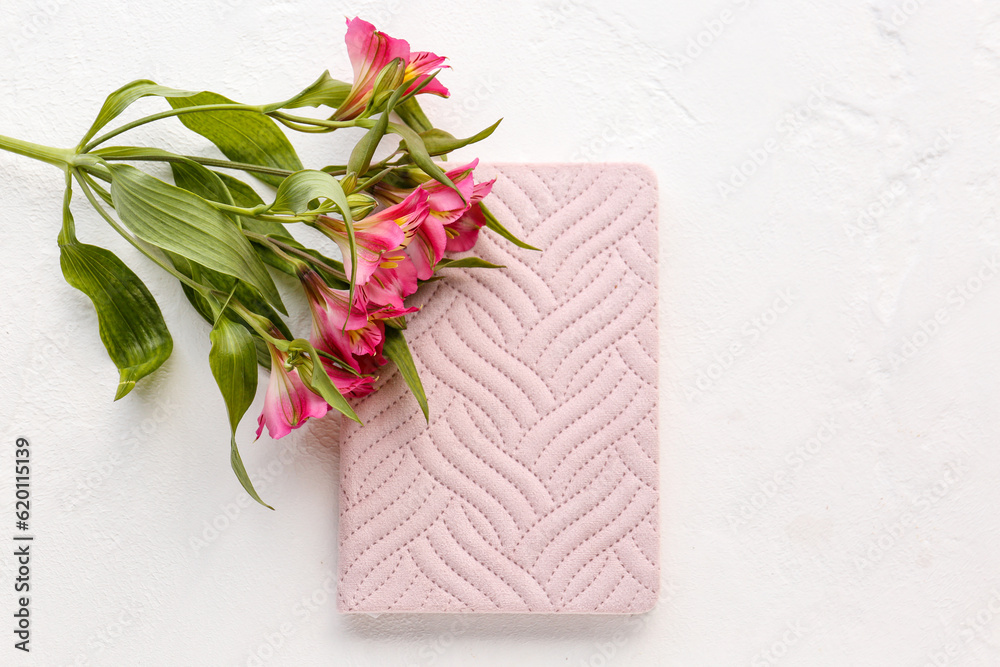 Notebook and beautiful alstroemeria flowers on light background