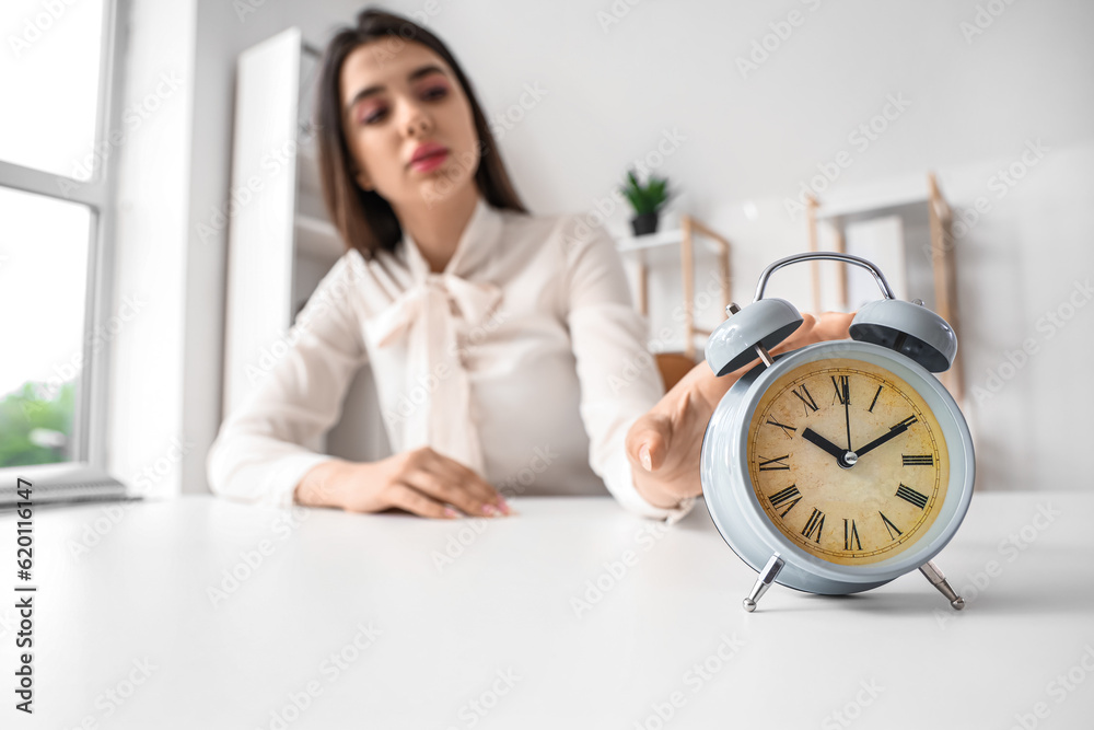 Businesswoman touching alarm clock in office. Time management concept