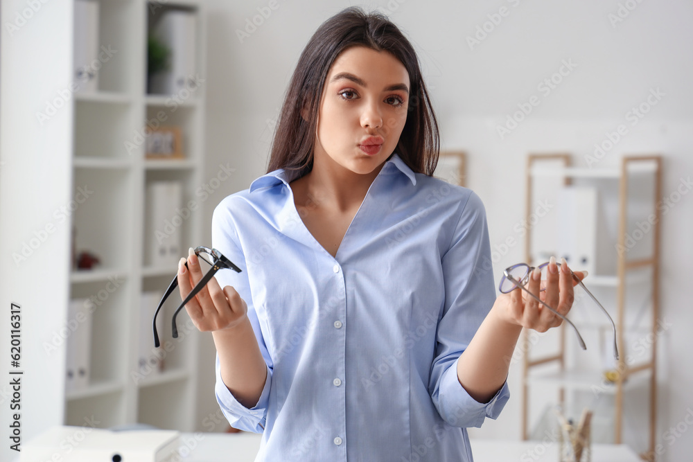 Doubtful young woman with glasses in office