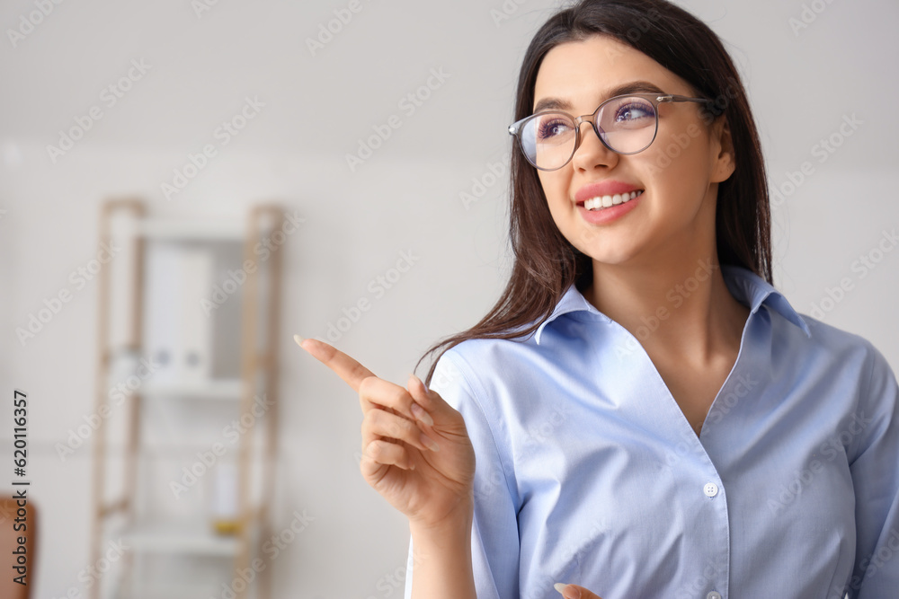 Beautiful young woman wearing glasses and pointing at something in office