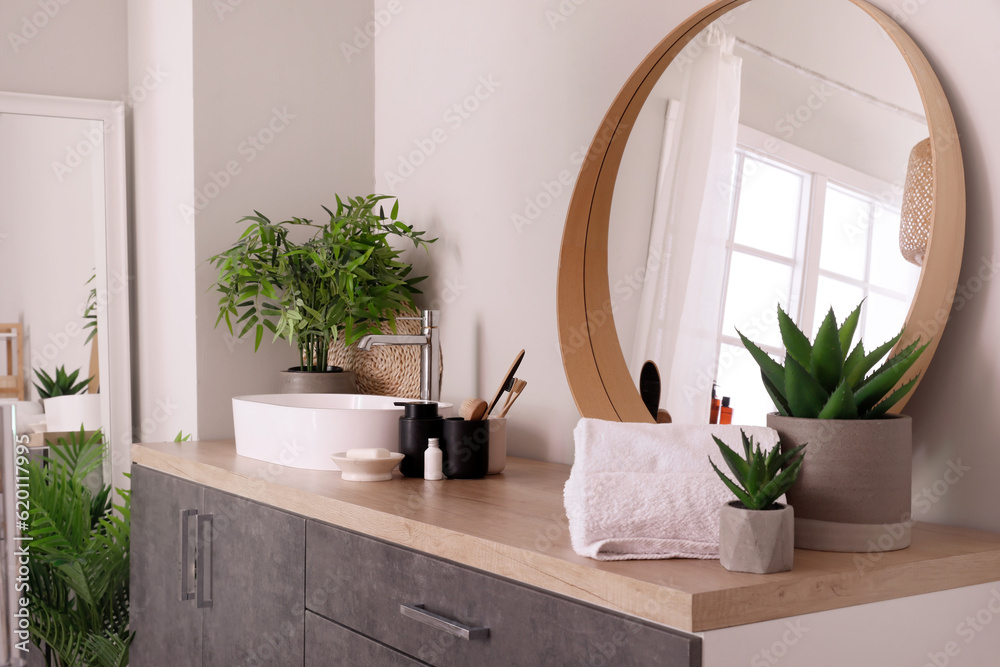 Sink bowl and bath accessories on wooden counter in bathroom