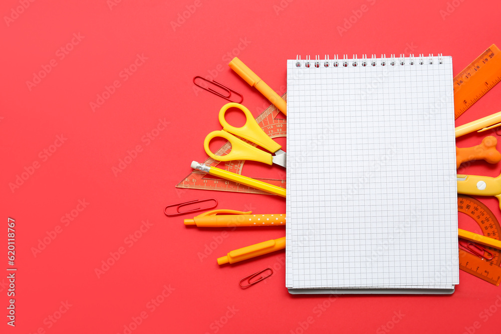 Composition with blank notebook and school stationery on red background