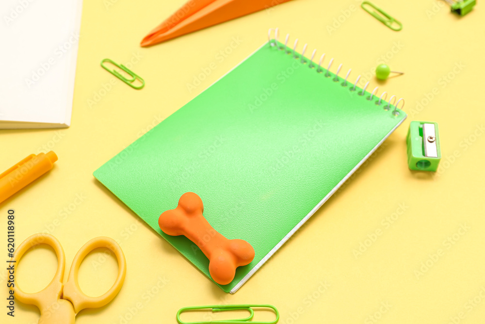 Notebook and different school stationery on yellow background, closeup