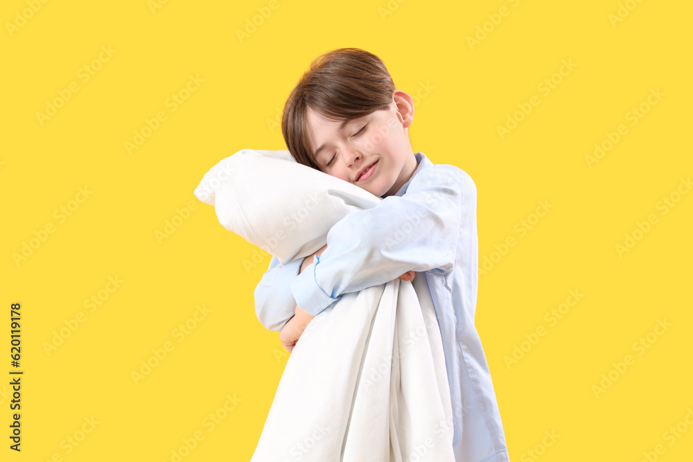 Cute little boy with blanket on yellow background