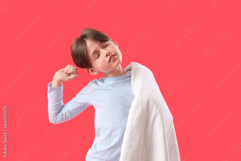 Sleepy little boy with blanket on red background