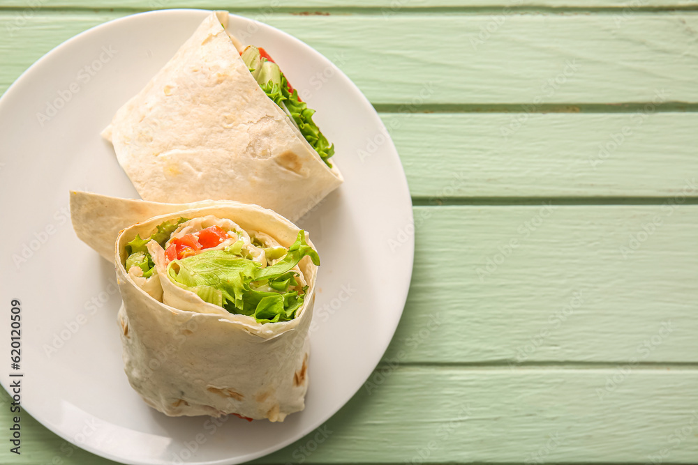 Plate of tasty lavash rolls with tomatoes and greens on green wooden background