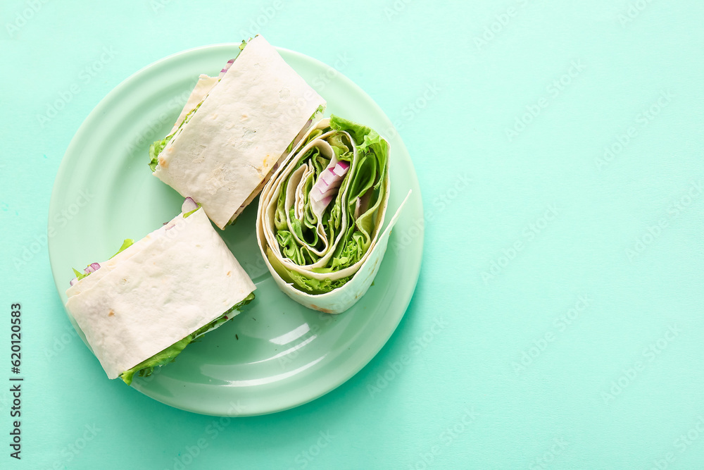 Plate of tasty lavash rolls with onion and greens on turquoise background