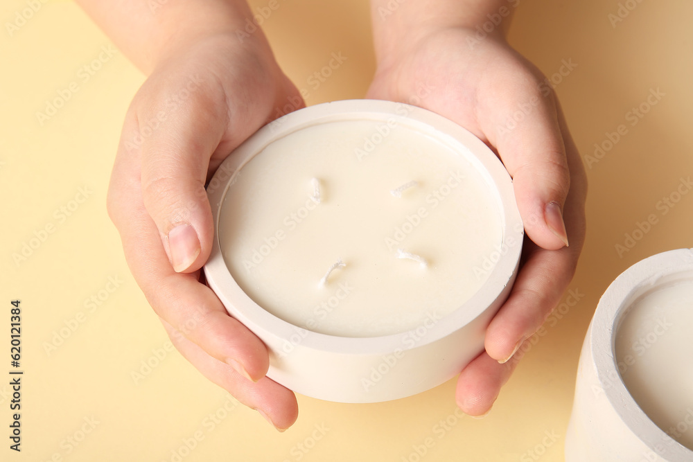 Female hands with candles on yellow background