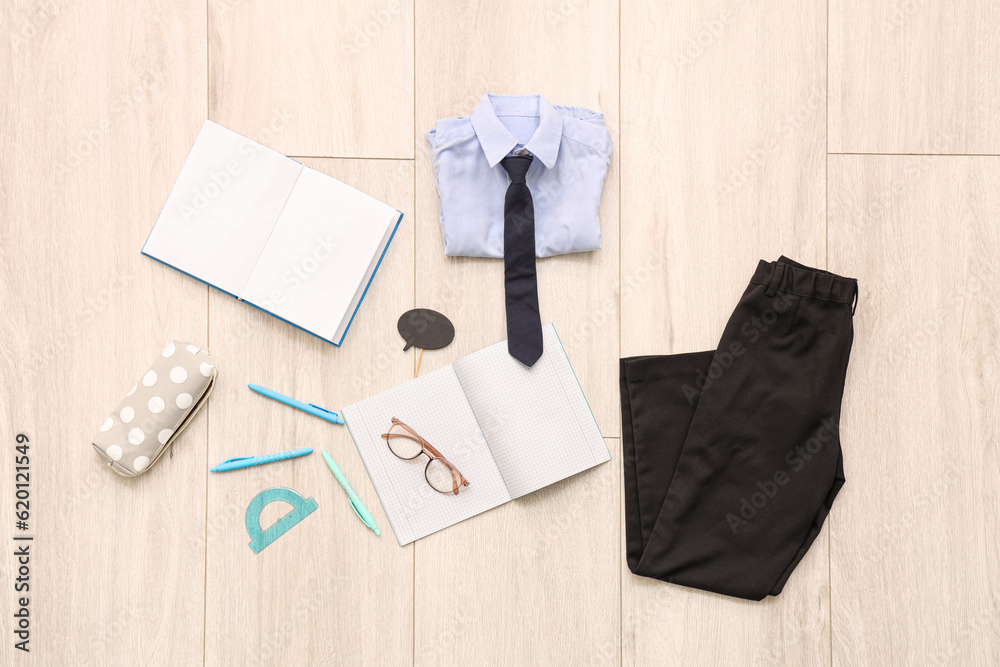 Composition with stylish school uniform, eyeglasses and stationery on wooden background