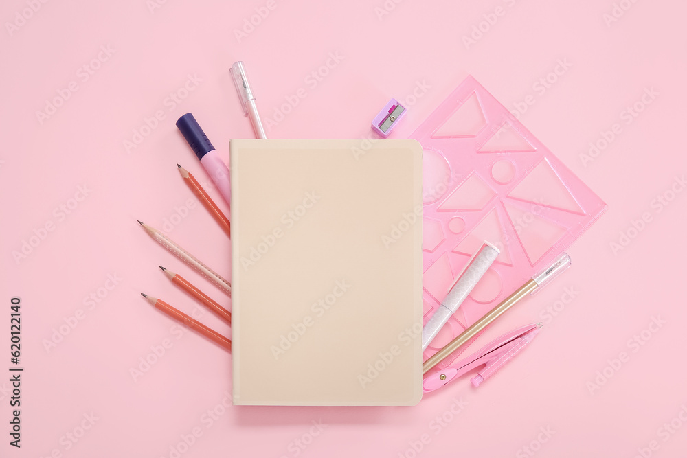 Notebook with different stationery on pink background