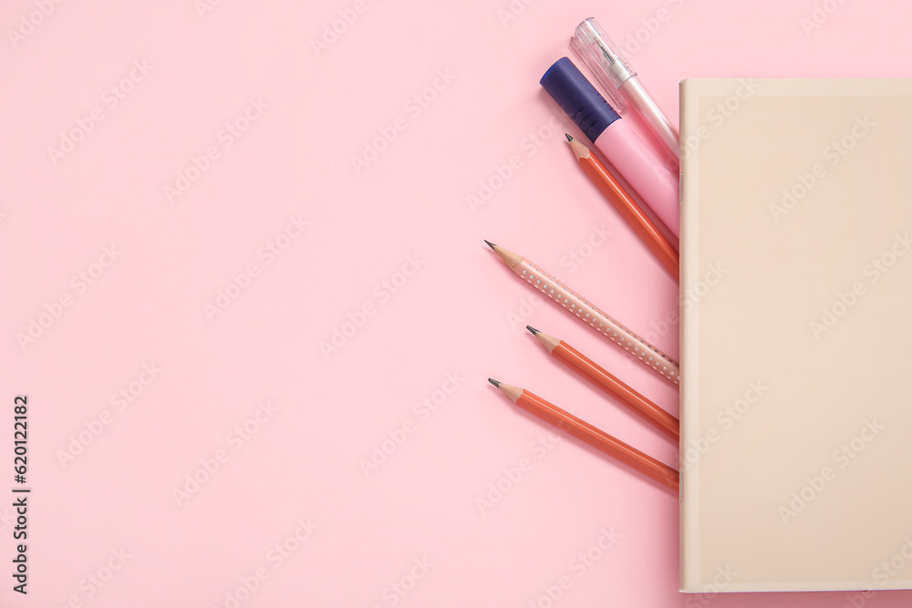 Notebook with different stationery on pink background