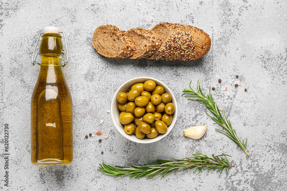 Bowl with ripe olives, bread and bottle of oil on light background