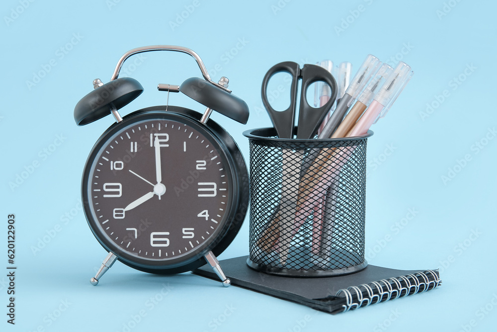 Alarm clock with different stationery on blue background