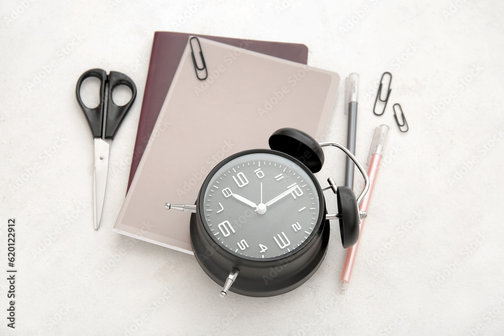 Alarm clock with different stationery on white background