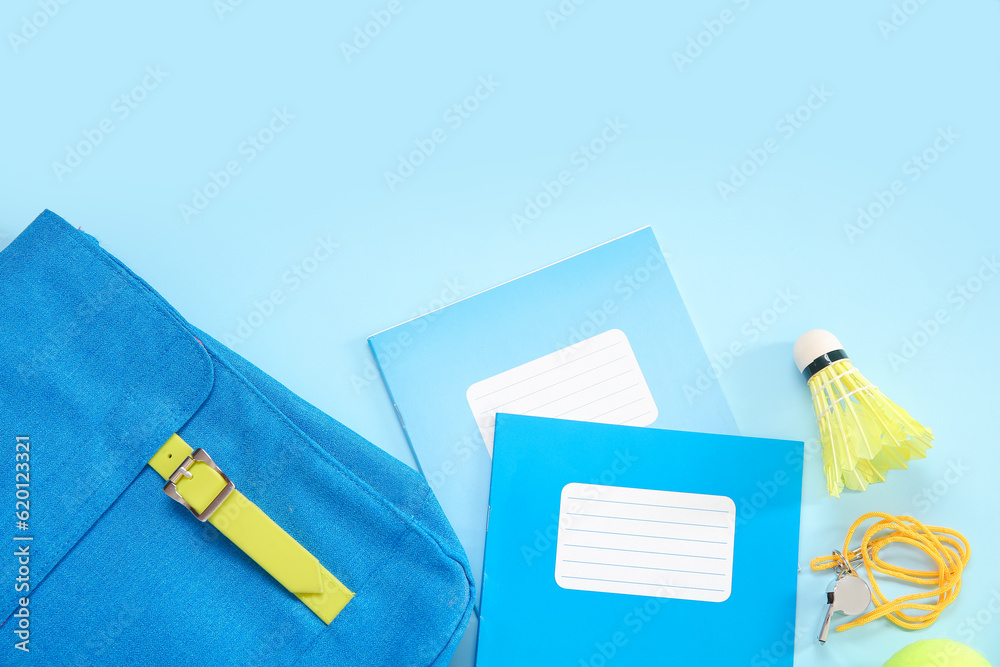 Backpack with tennis ball, whistle, badminton shuttlecock and notebooks on blue background