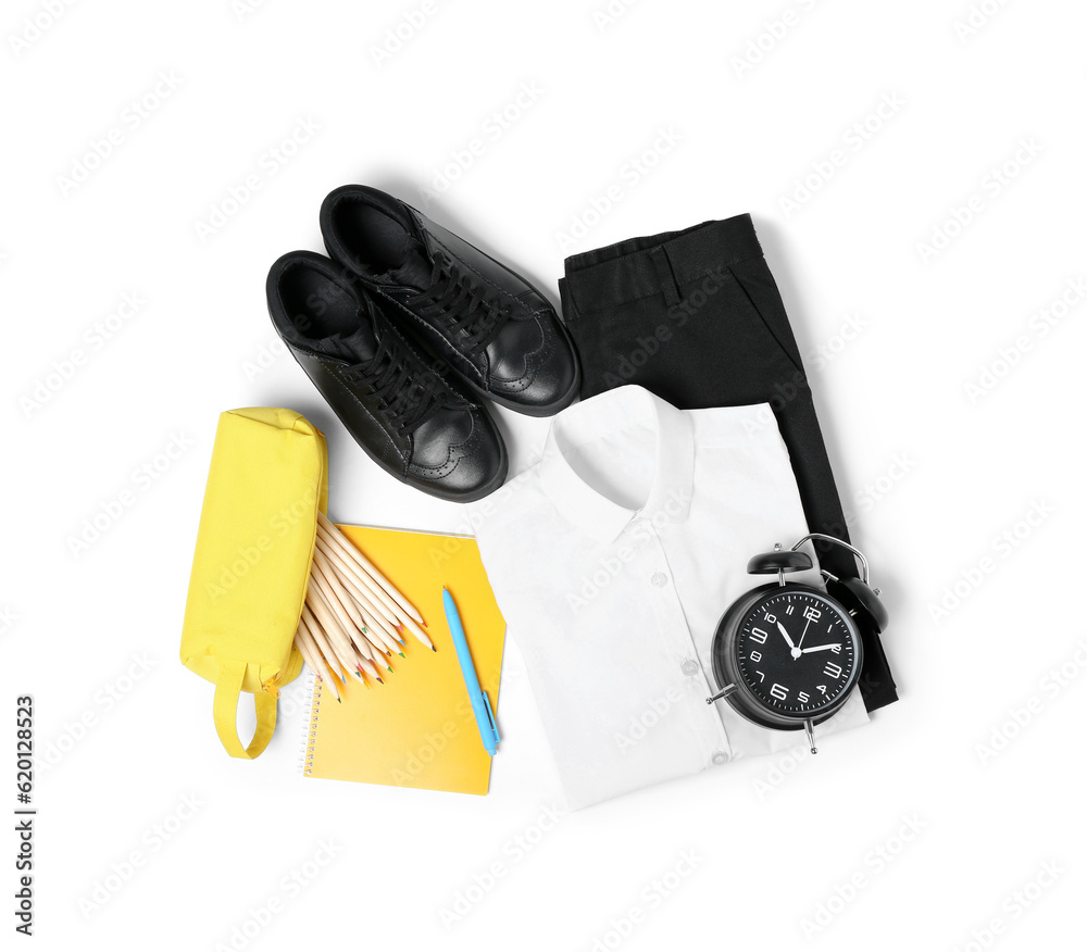 Stylish school uniform with alarm clock, pencil case and stationery isolated on white background