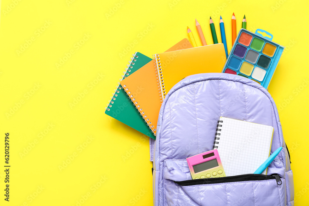 Backpack with blank notebook and different stationery on yellow background