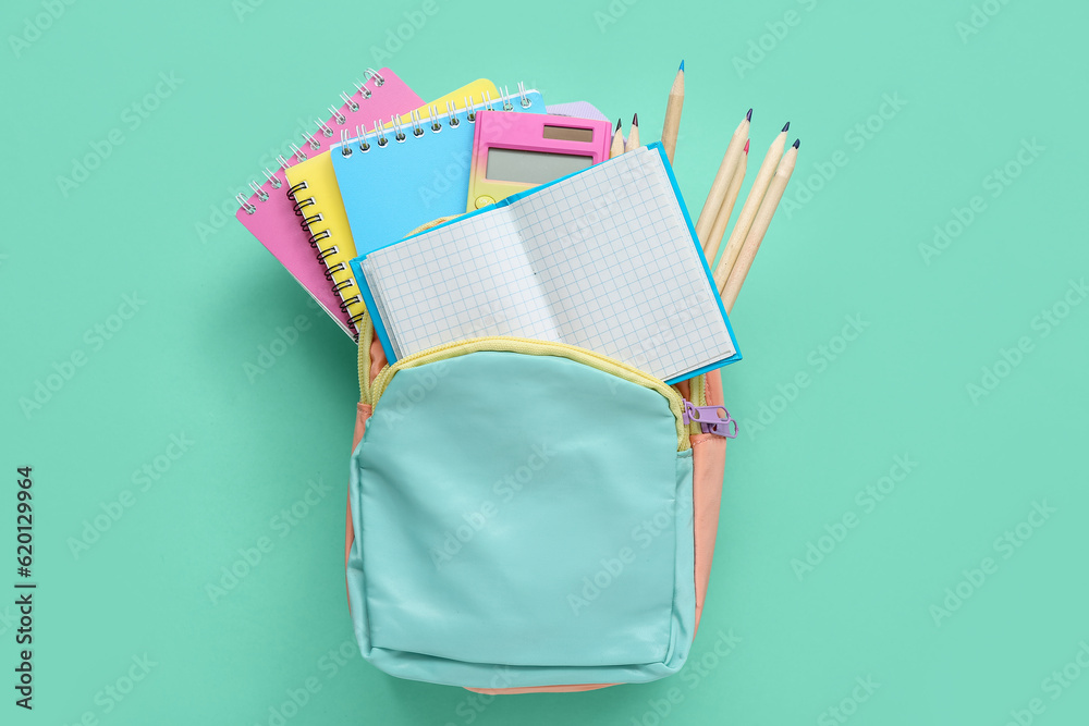 Backpack with blank notebook and stationery on turquoise background