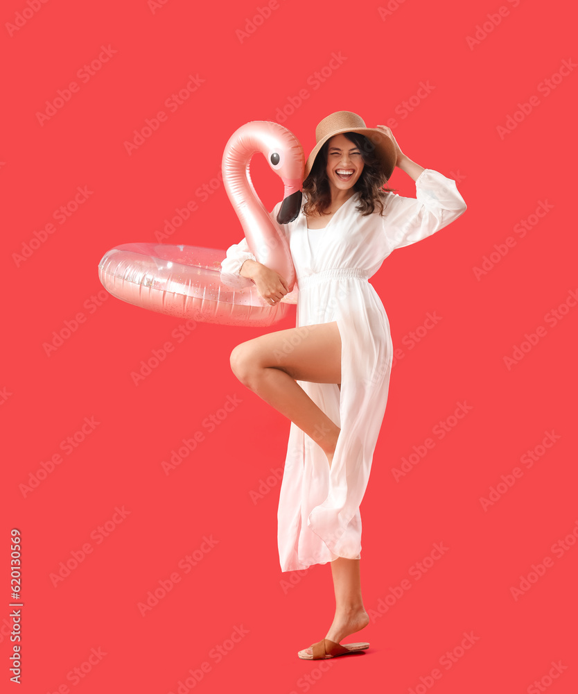 Young woman with inflatable ring on red background