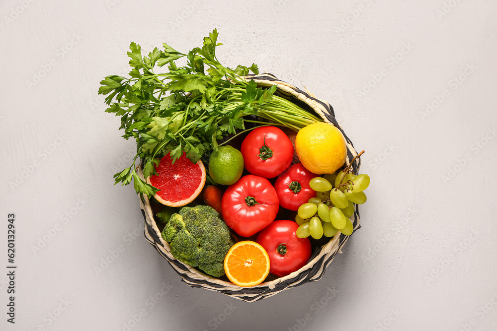 Wicker bowl with different fresh fruits and vegetables on white background