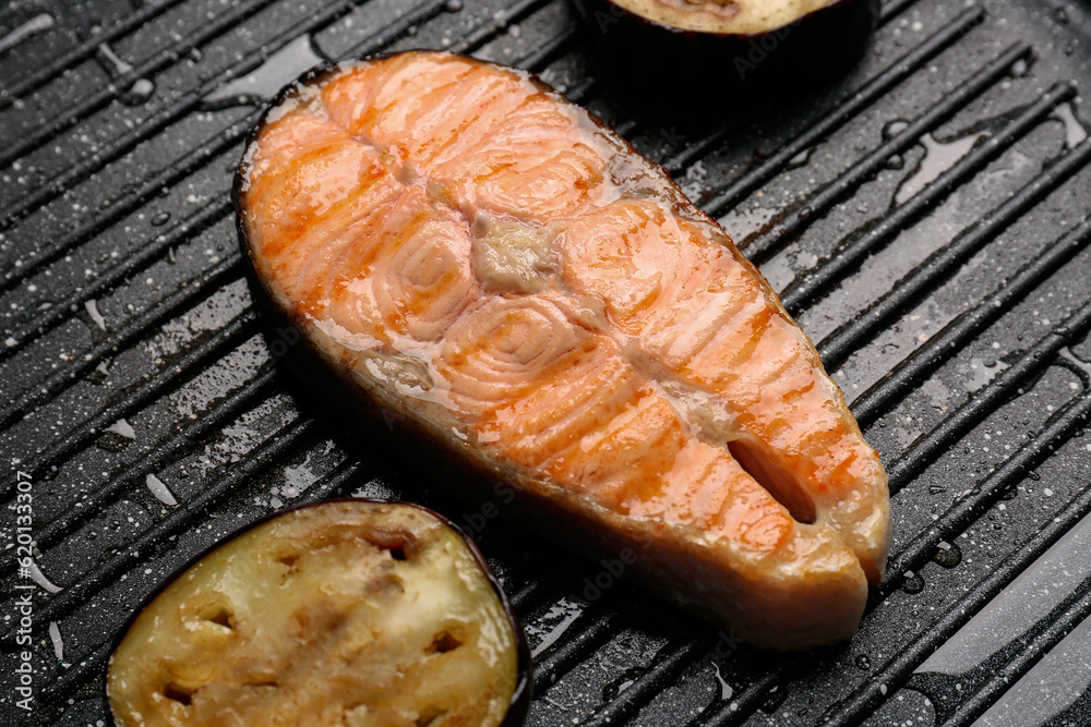 Tasty grilled salmon steak in frying pan, closeup