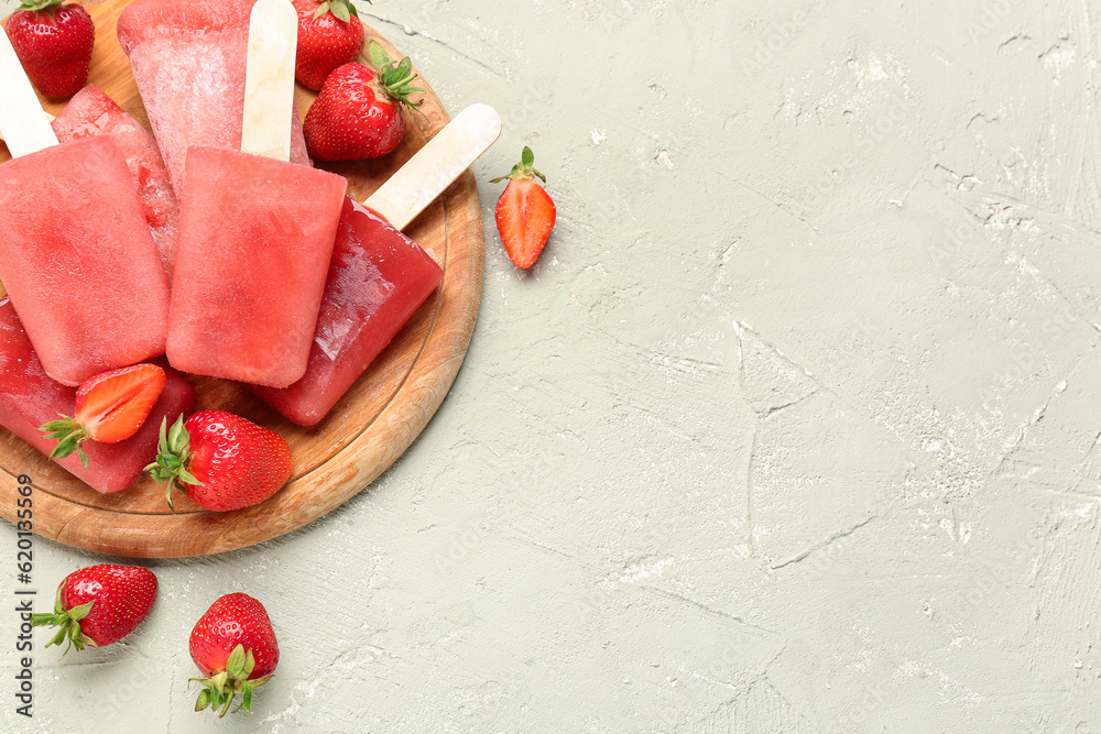 Wooden board with sweet strawberry ice-cream popsicles on grey background