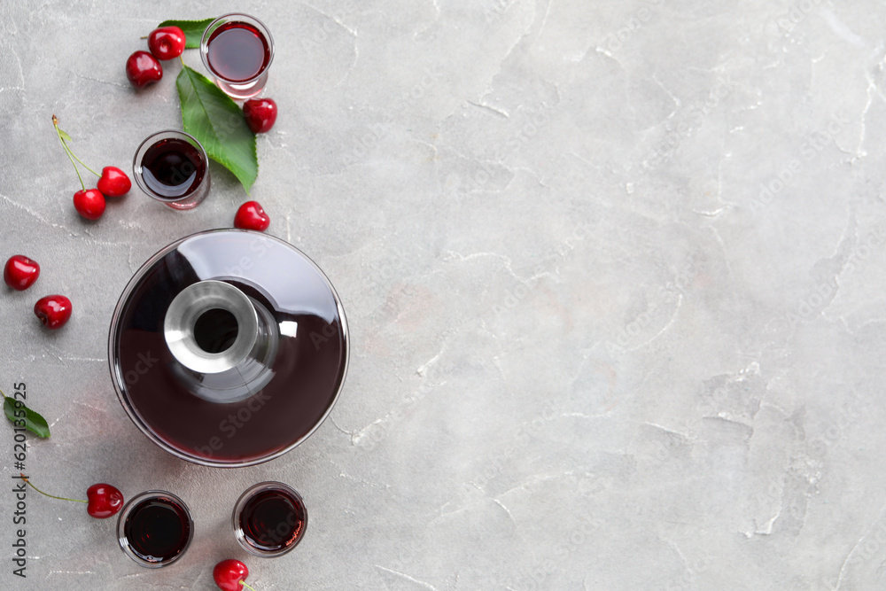 Shots and bottle with sweet cherry liqueur on grey background