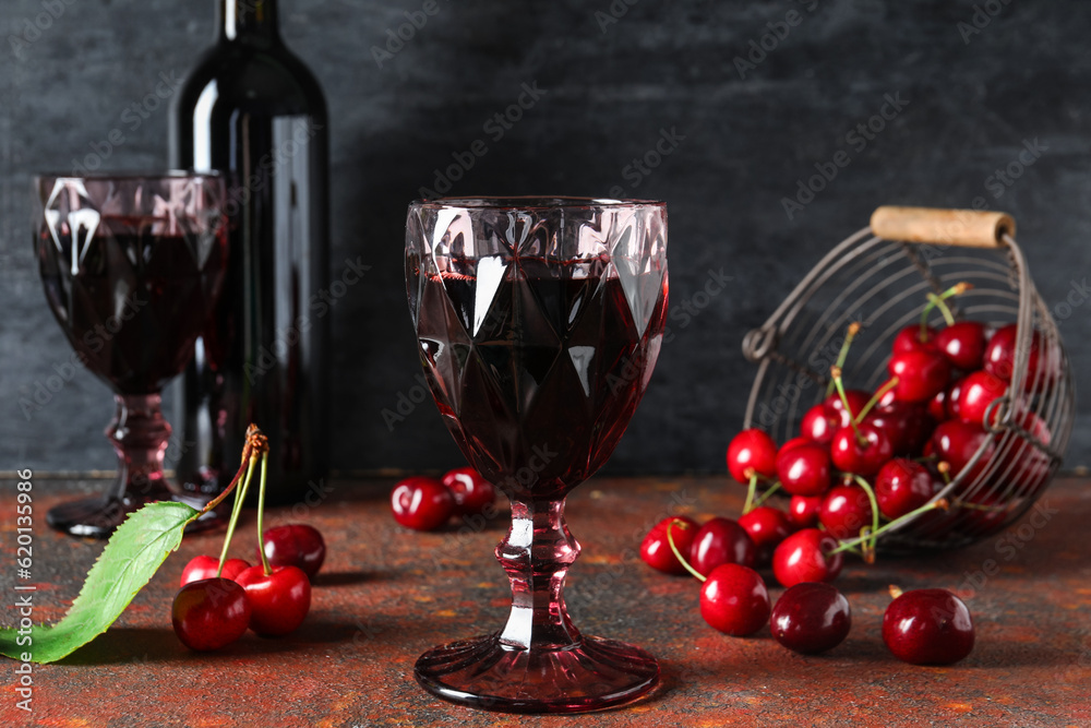 Glasses and bottle with sweet cherry liqueur on red table