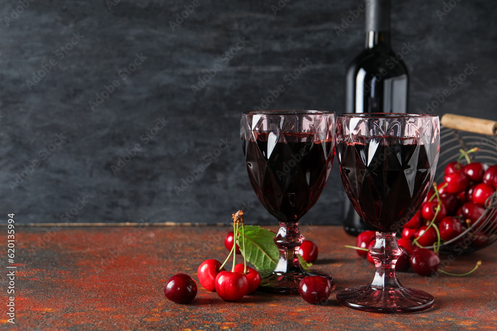 Glasses and bottle with sweet cherry liqueur on red table