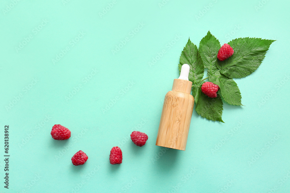 Bottle of cosmetic raspberry oil on blue background