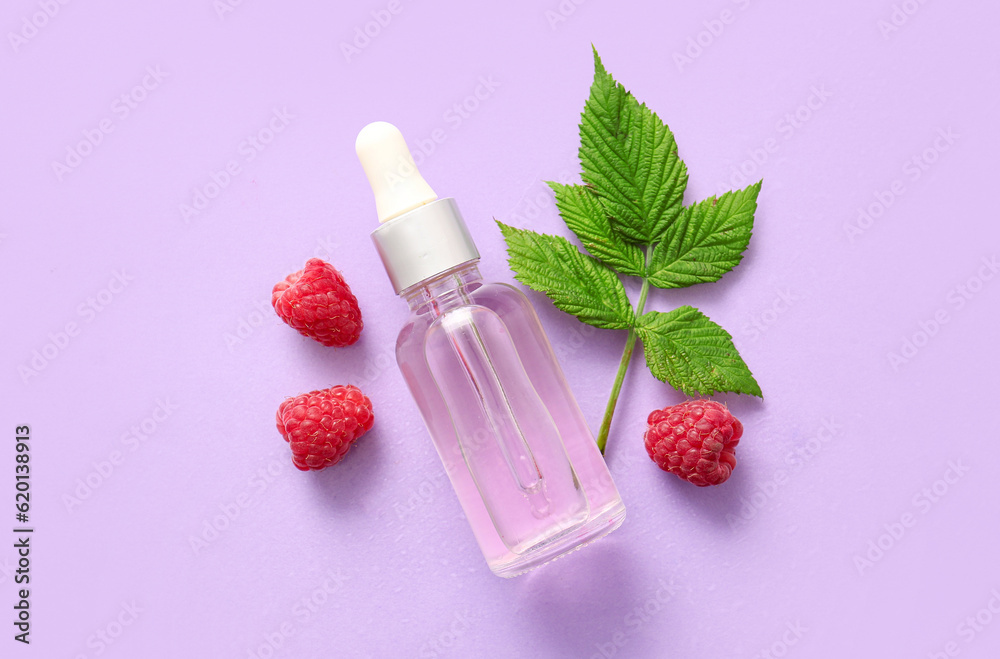 Bottle of cosmetic raspberry oil on lilac background