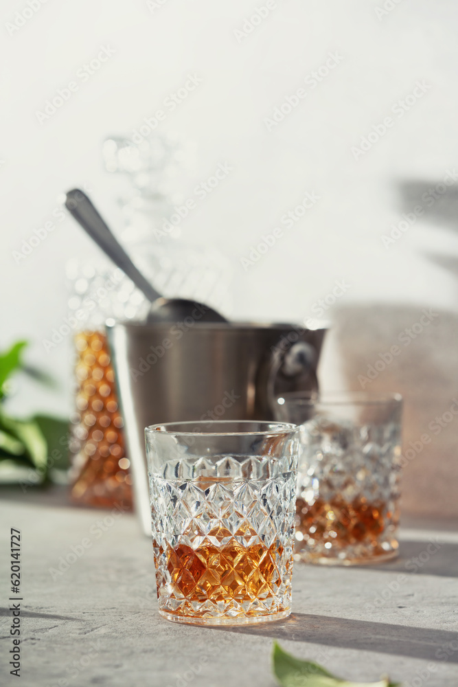 Glass of whiskey with ice cubes, ice bucket and carafe close up