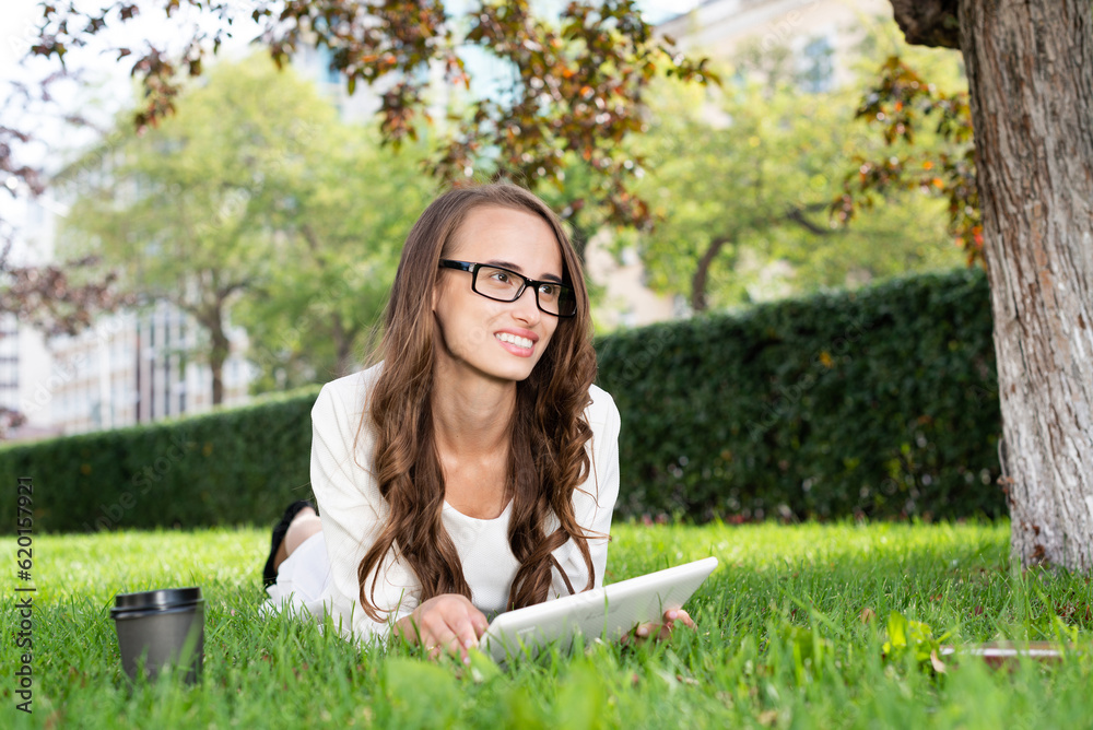 Young woman with digital tablet laying on grass