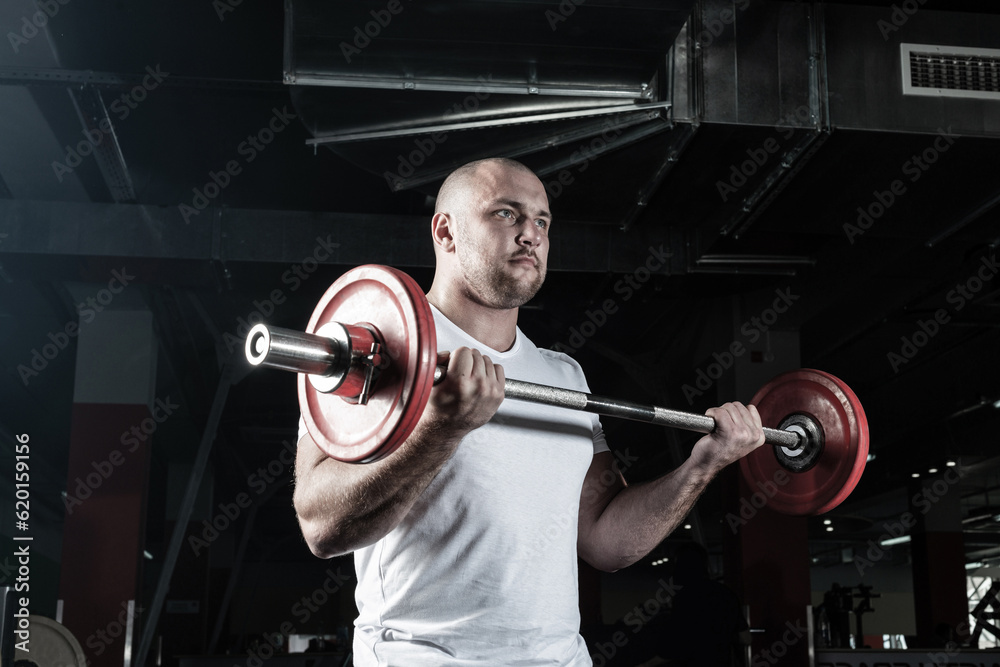 Male athlete lifts the barbell