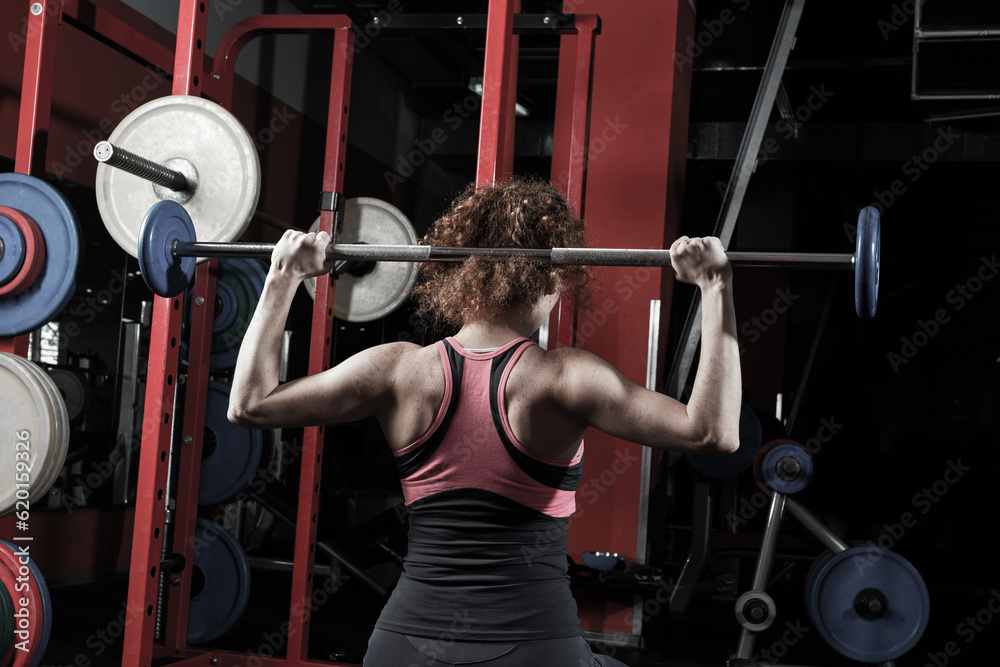 Woman bodybuilder engaged with a barbell in the gym