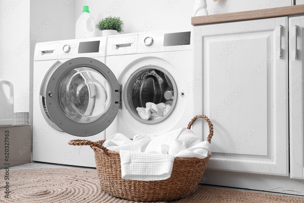 Modern washing machines with dirty clothes in laundry room