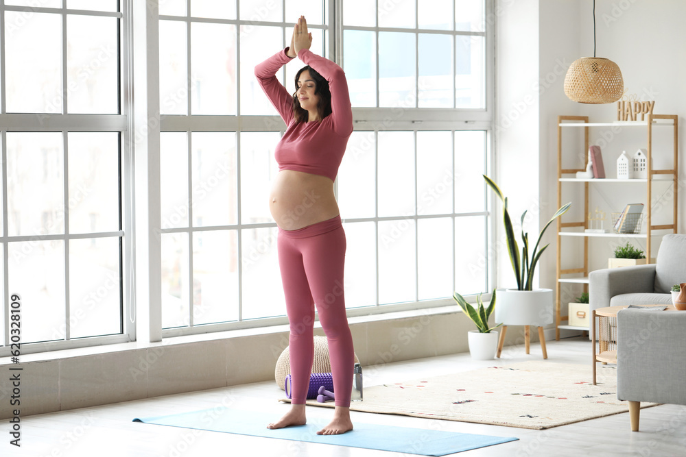 Sporty pregnant woman meditating at home